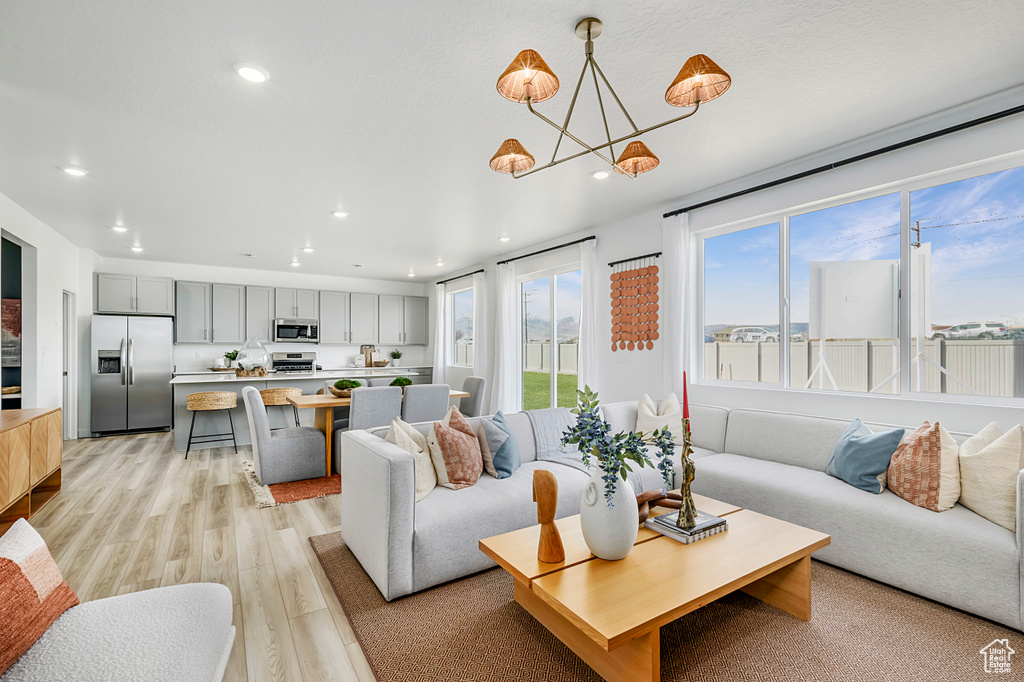 Living area featuring light wood-style floors, recessed lighting, and a notable chandelier