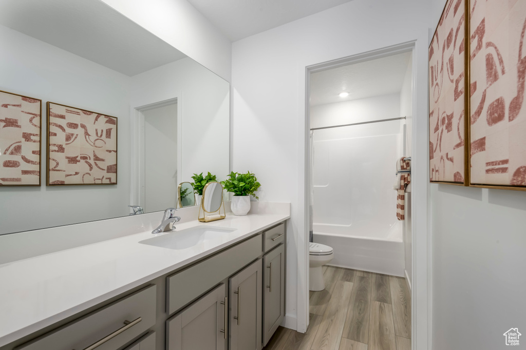 Full bath with toilet, wood finished floors, vanity, and shower / bathing tub combination