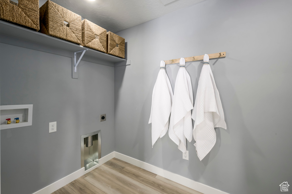 Laundry area with baseboards, laundry area, wood finished floors, electric dryer hookup, and hookup for a washing machine