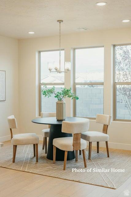 Dining room with a chandelier, wood finished floors, baseboards, and recessed lighting