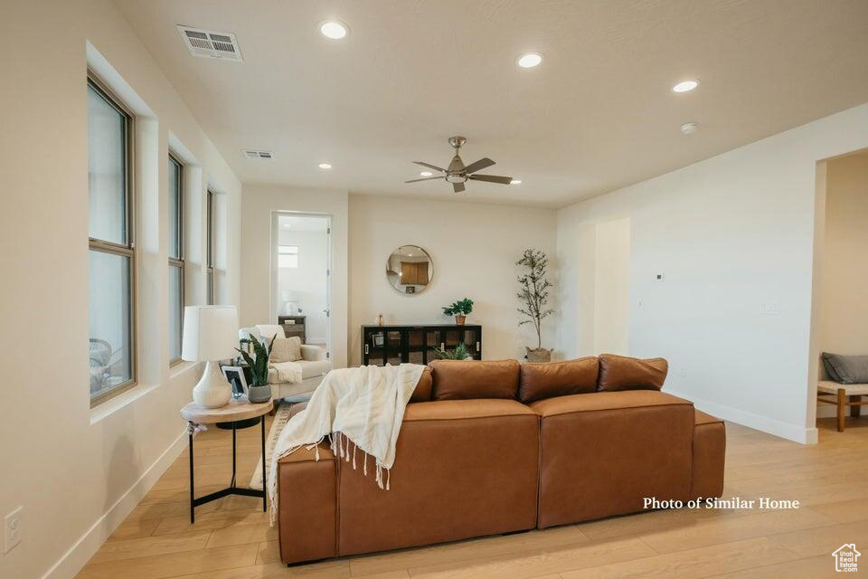 Living area featuring visible vents, a ceiling fan, light wood-style flooring, and a healthy amount of sunlight