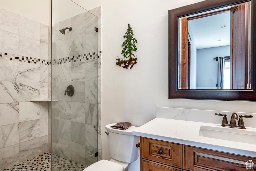 Bathroom with tiled shower, vanity, and toilet