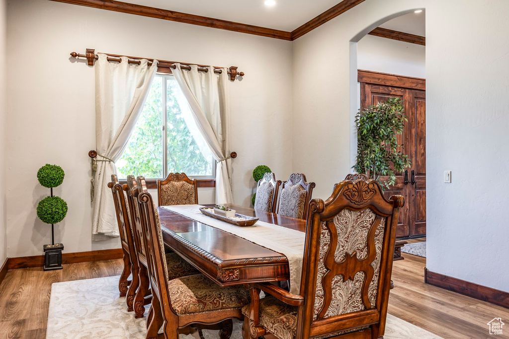Dining room featuring crown molding, arched walkways, wood finished floors, and baseboards