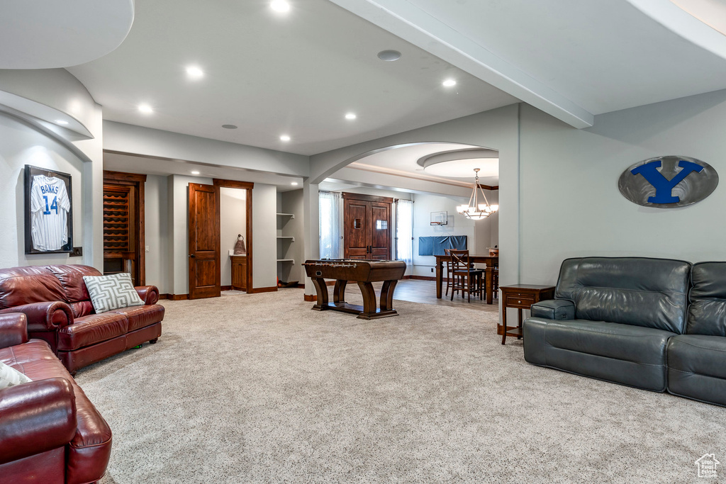 Carpeted living room with beamed ceiling, arched walkways, recessed lighting, a chandelier, and baseboards