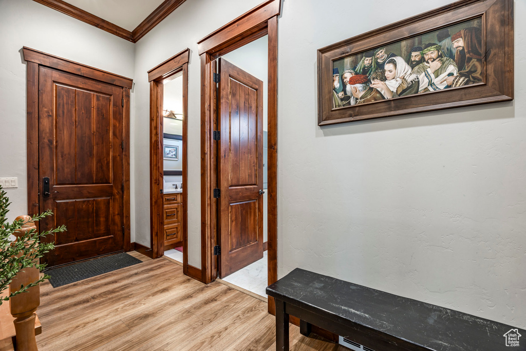 Foyer with crown molding, baseboards, and light wood-style floors