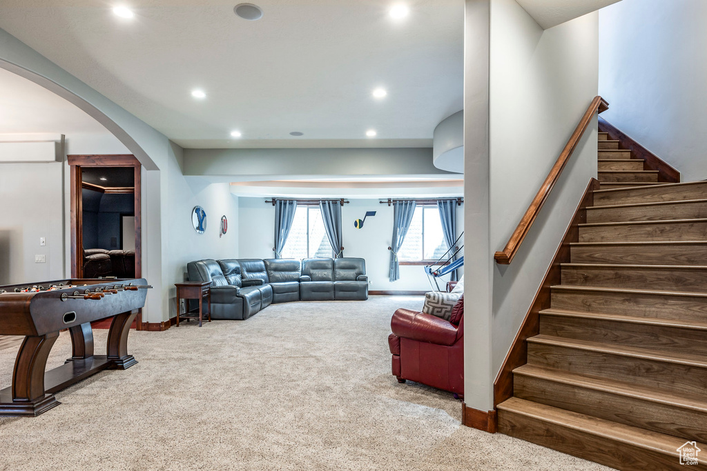 Carpeted living area with baseboards, stairway, arched walkways, and recessed lighting