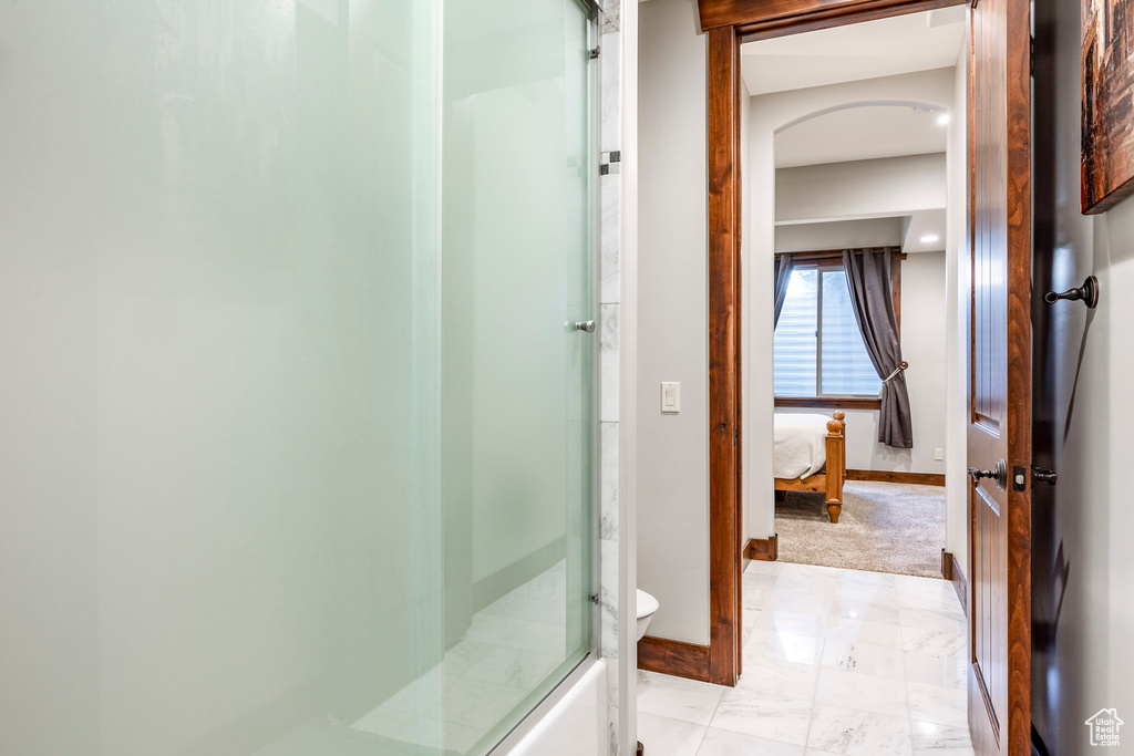 Full bath featuring baseboards, an enclosed shower, connected bathroom, toilet, and marble finish floor