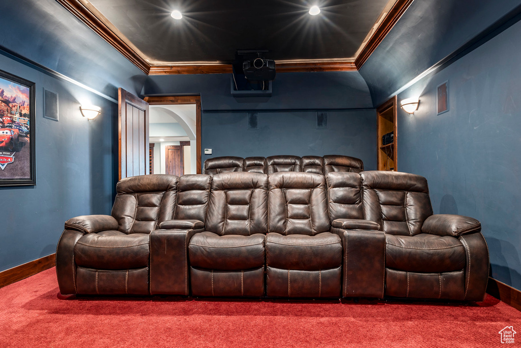 Carpeted home theater with crown molding and baseboards