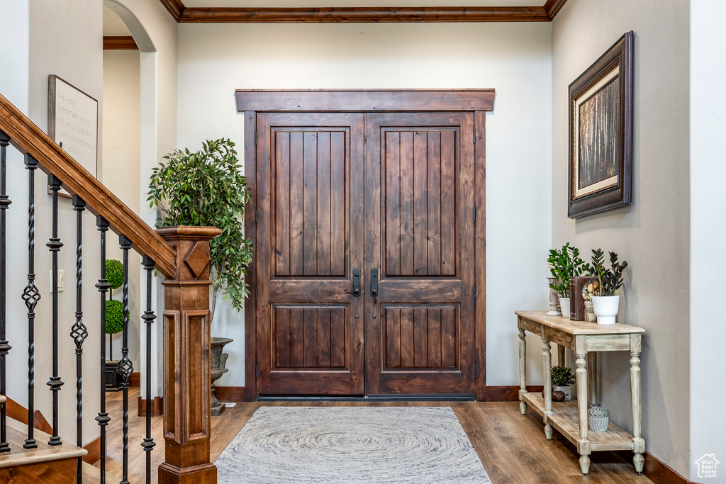 Foyer entrance featuring dark wood-type flooring, ornamental molding, stairway, and arched walkways