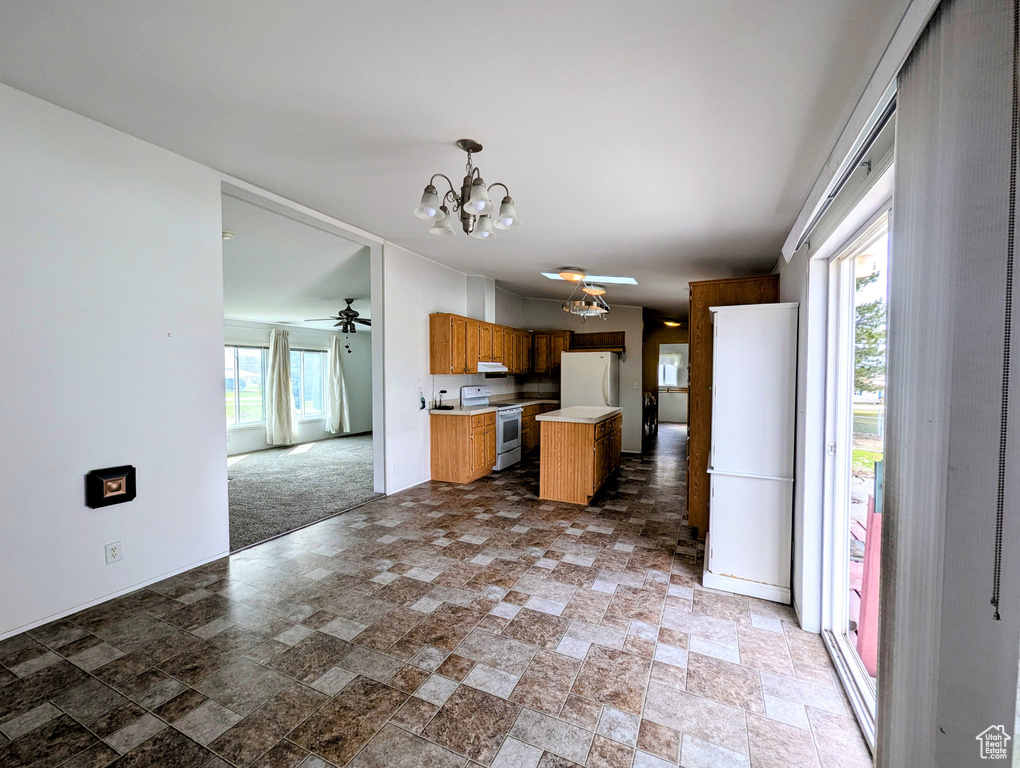 Kitchen with open floor plan, light countertops, white appliances, under cabinet range hood, and ceiling fan with notable chandelier