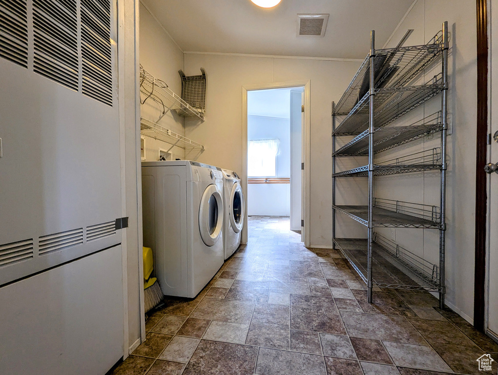Clothes washing area with visible vents, laundry area, stone finish flooring, a heating unit, and washing machine and clothes dryer