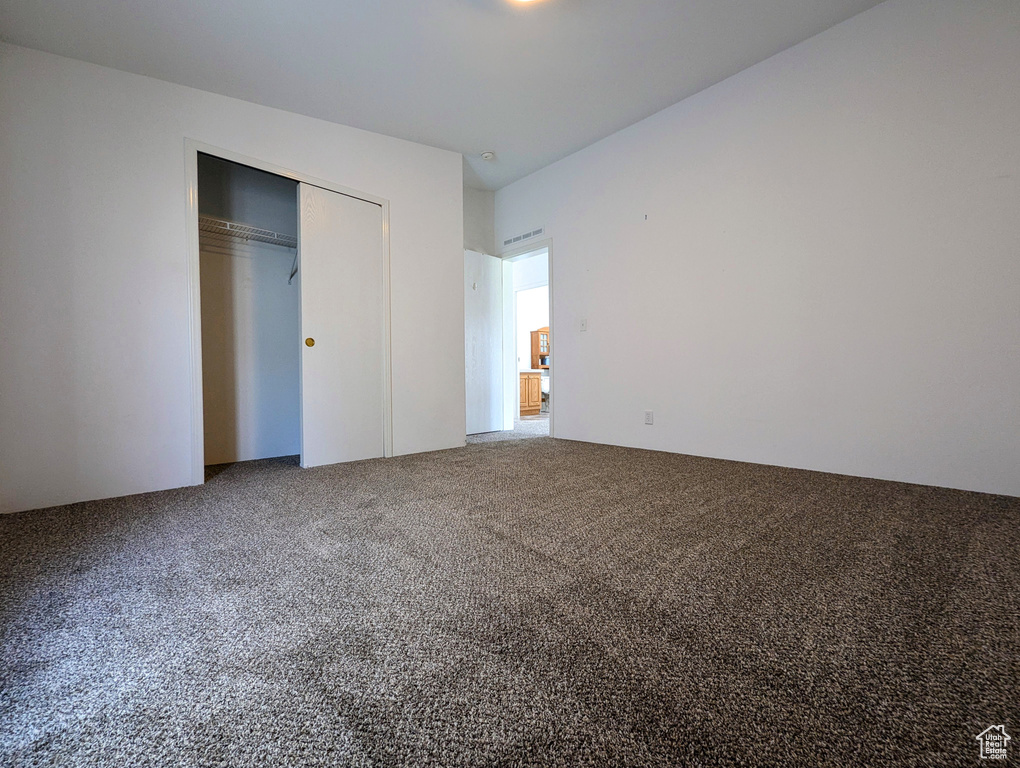 Unfurnished bedroom featuring a closet, carpet flooring, and visible vents
