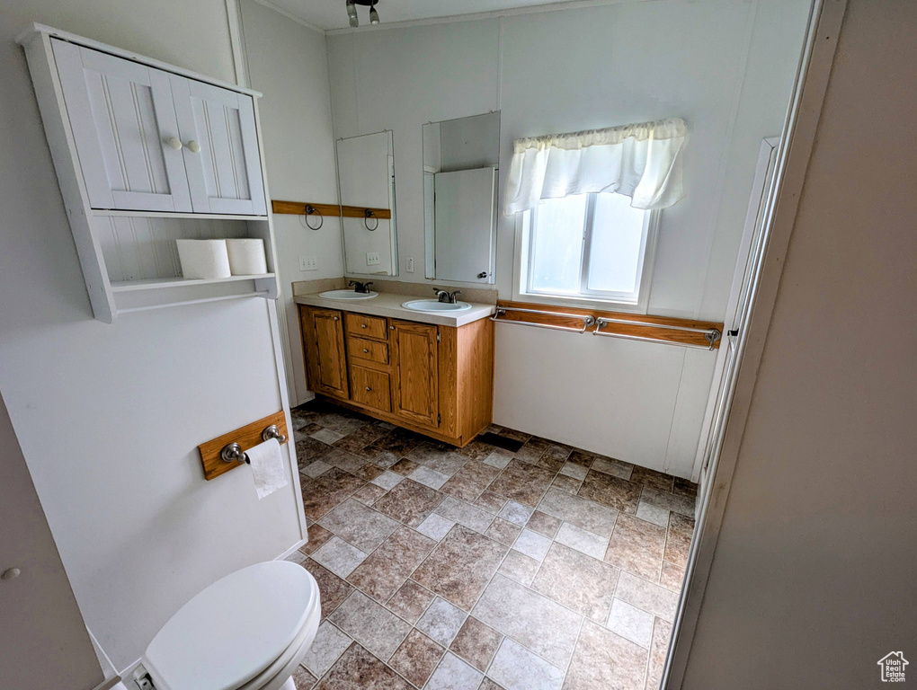Full bath featuring double vanity, stone finish floor, a sink, and toilet