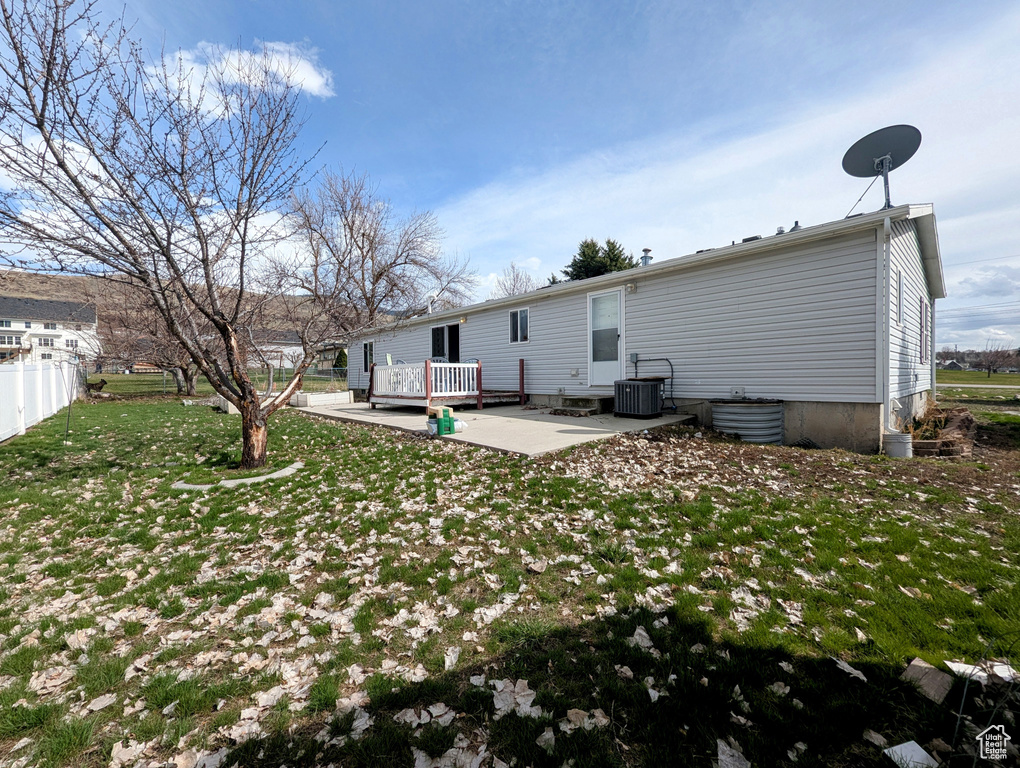 Rear view of house with a patio area, central AC, a wooden deck, a yard, and fence