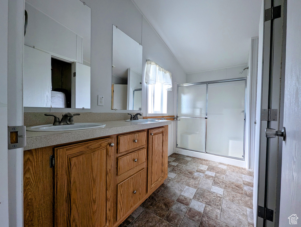 Full bath with stone finish flooring, double vanity, a sink, and a stall shower