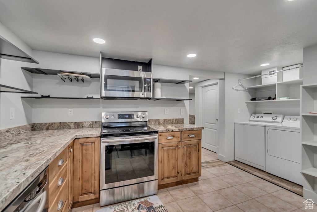 Kitchen featuring separate washer and dryer, brown cabinetry, open shelves, and appliances with stainless steel finishes