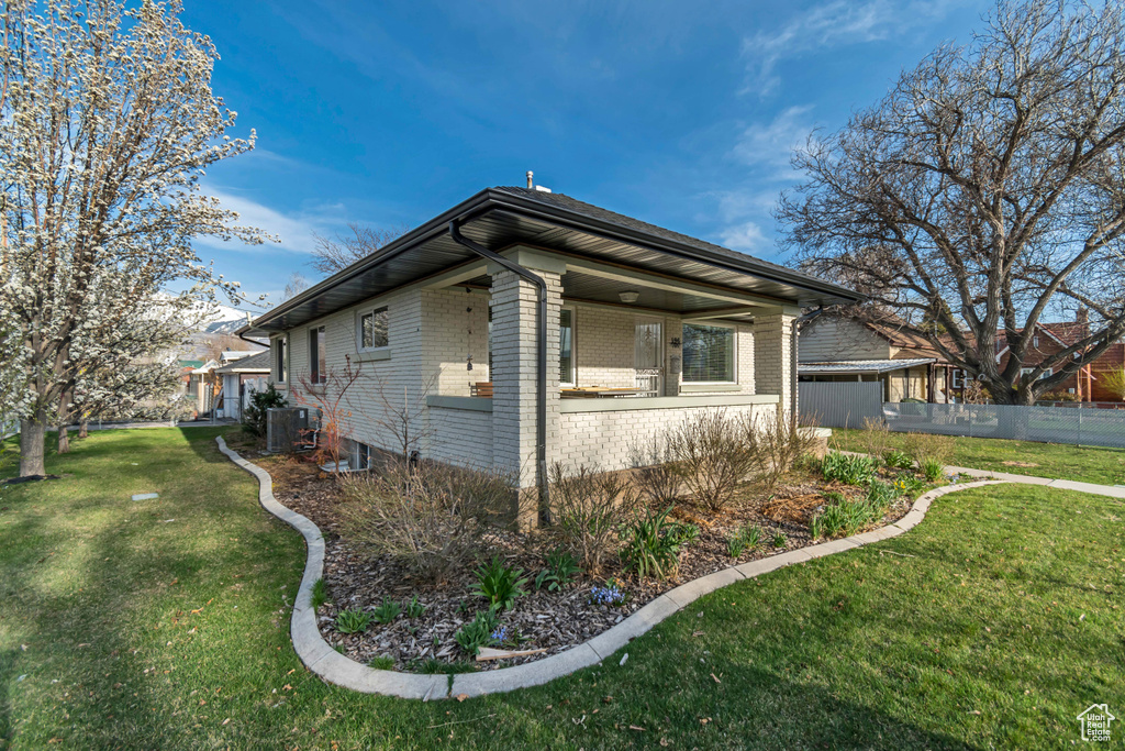 View of home's exterior featuring a yard, brick siding, central AC, and fence