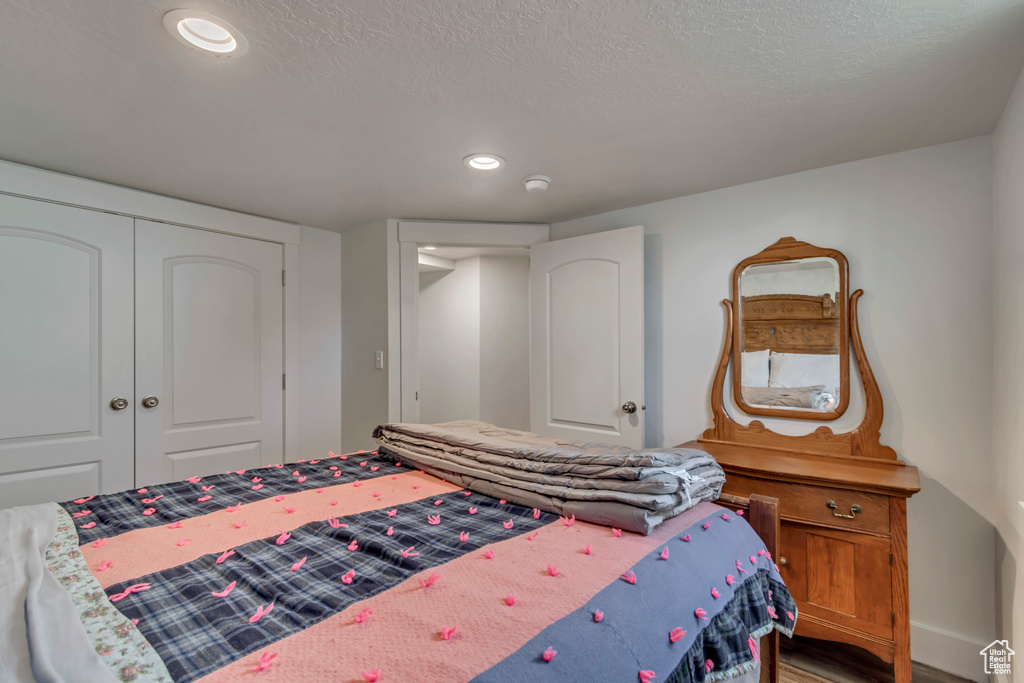 Bedroom with a closet, recessed lighting, wood finished floors, and a textured ceiling