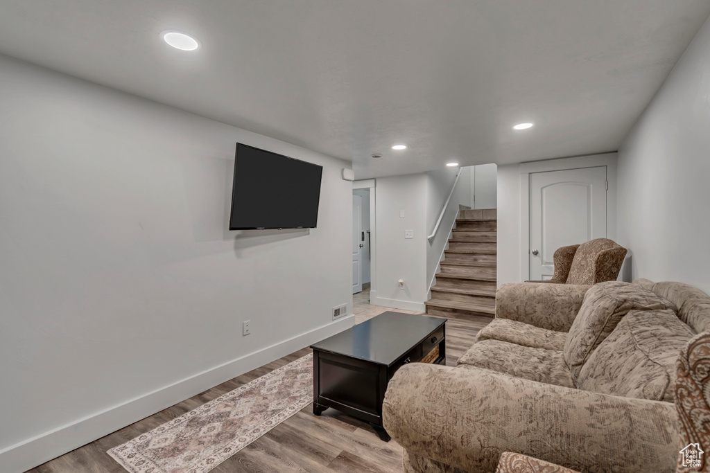 Living room with baseboards, light wood finished floors, recessed lighting, and stairs