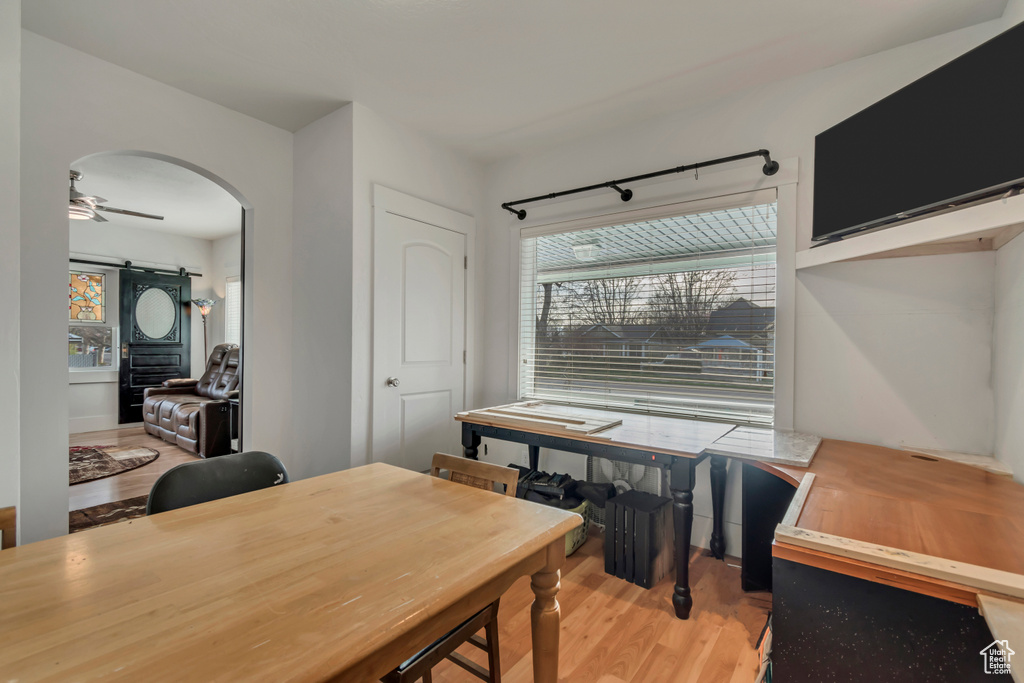 Office area featuring light wood finished floors, arched walkways, and a ceiling fan