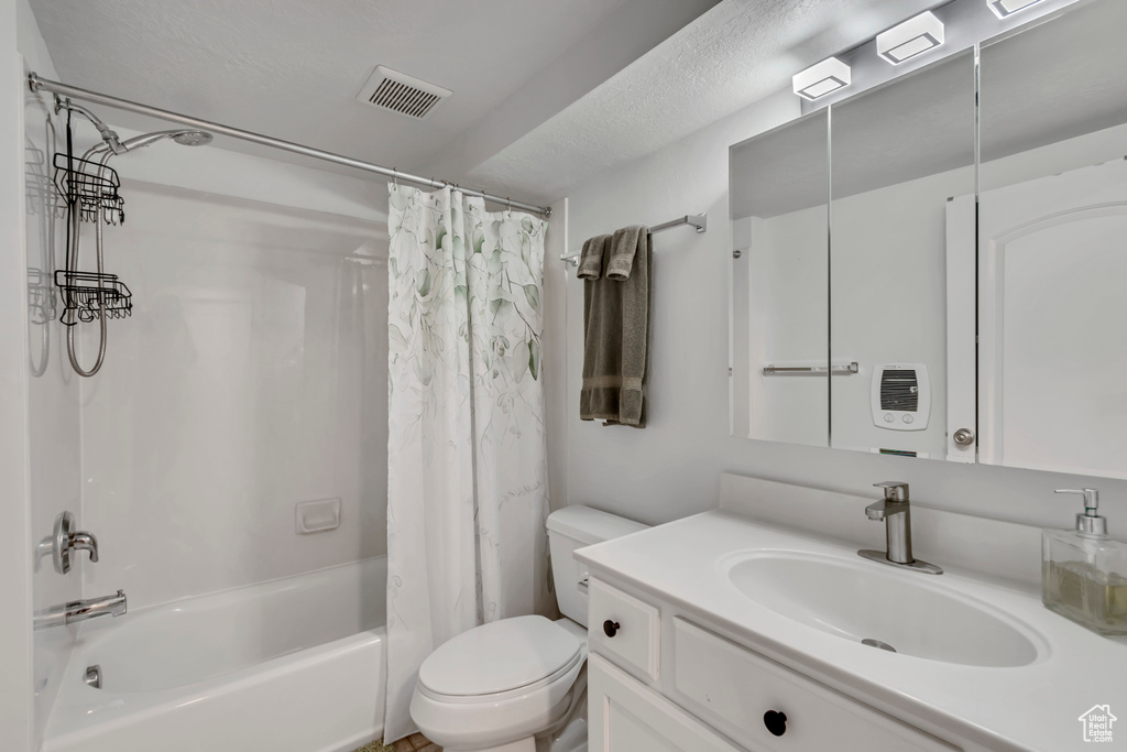 Bathroom featuring shower / bath combo, visible vents, toilet, and vanity