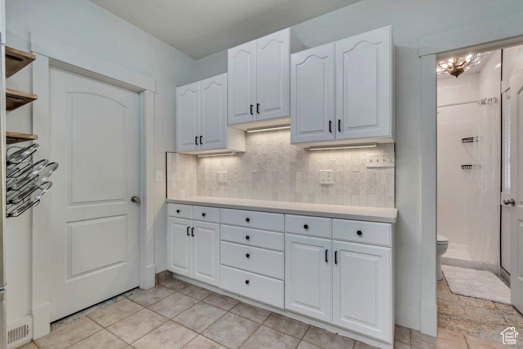 Kitchen featuring light tile patterned floors, open shelves, white cabinetry, light countertops, and decorative backsplash