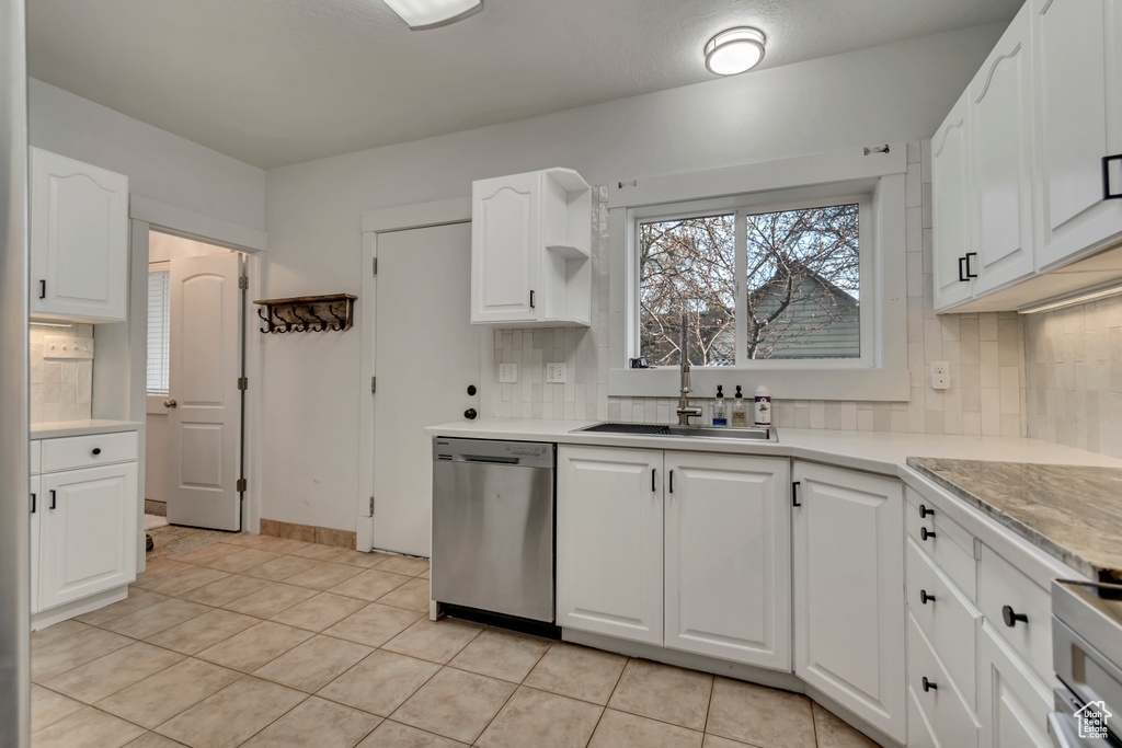 Kitchen featuring range, light countertops, white cabinetry, stainless steel dishwasher, and a sink