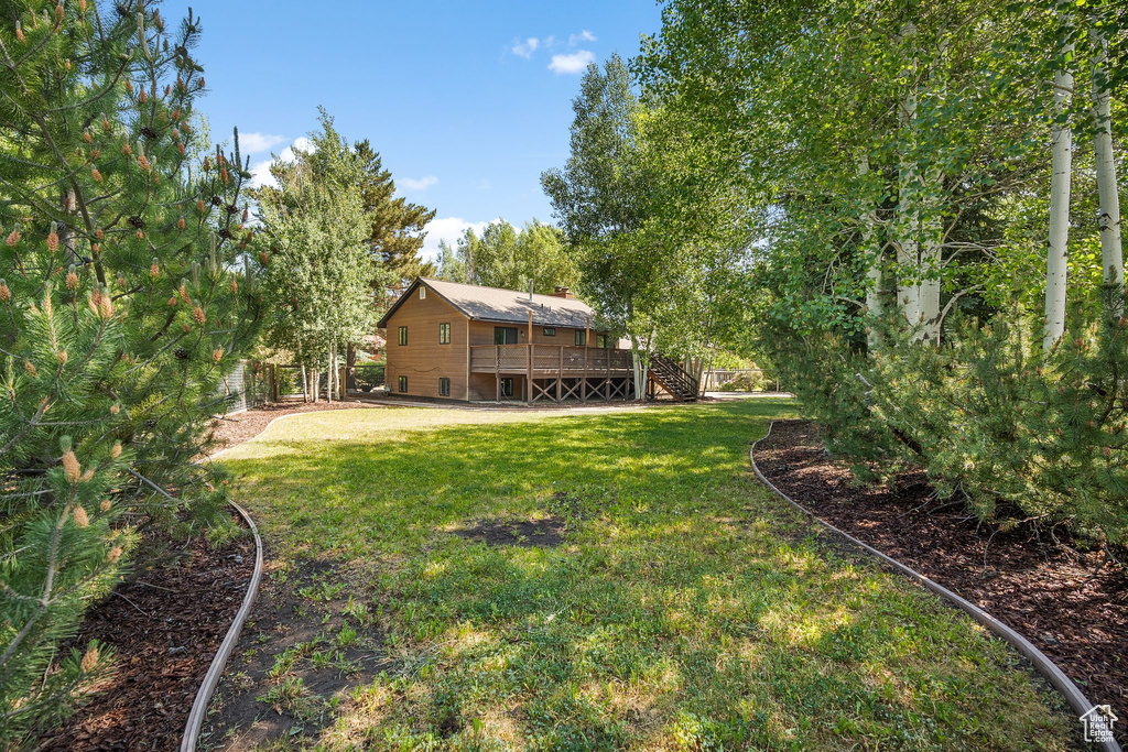 View of grassy yard featuring stairway and a deck