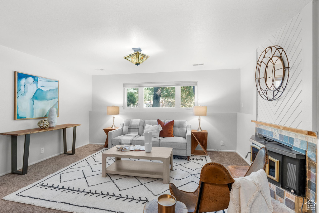 Carpeted living room featuring a tiled fireplace and baseboards