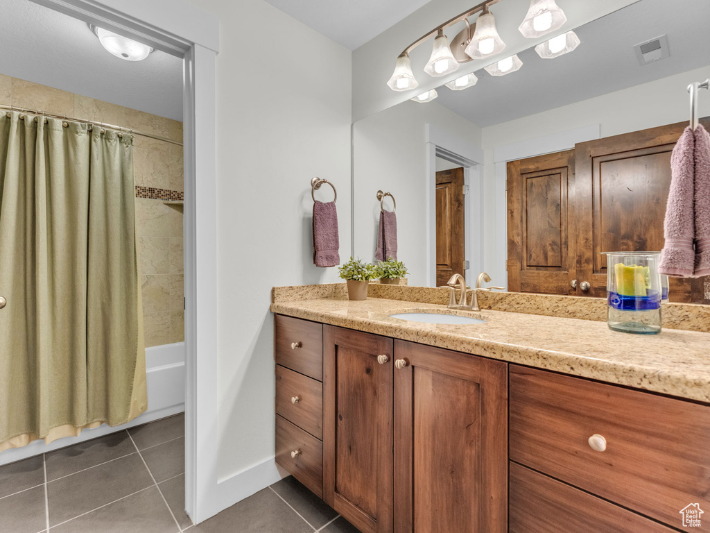 Full bath with tile patterned flooring, vanity, baseboards, and shower / tub combo