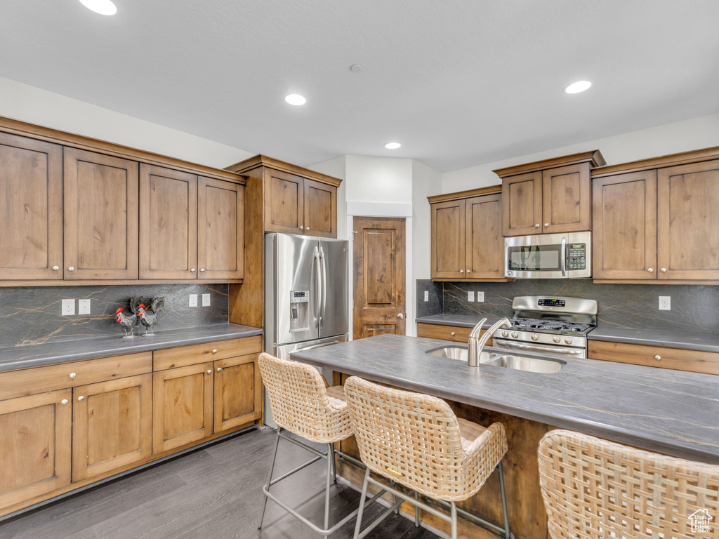 Kitchen featuring appliances with stainless steel finishes, a sink, a breakfast bar area, tasteful backsplash, and recessed lighting