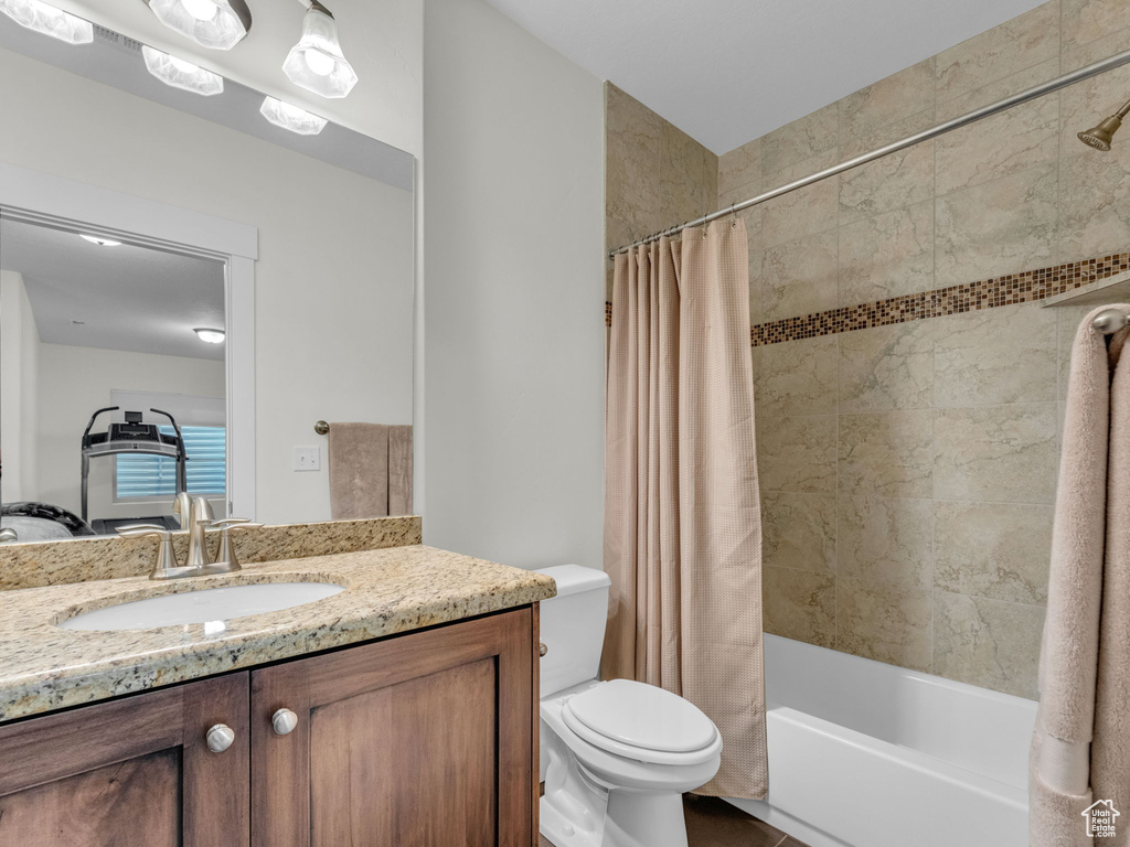 Bathroom featuring vanity, shower / bath combo, and toilet
