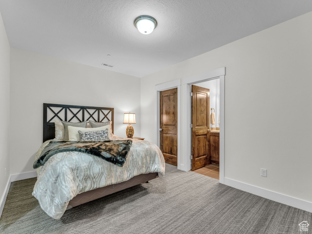 Carpeted bedroom featuring baseboards and connected bathroom