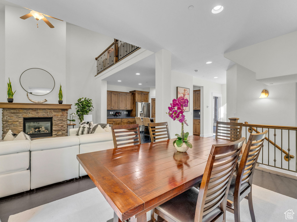 Dining space with a ceiling fan, recessed lighting, a stone fireplace, and light wood finished floors