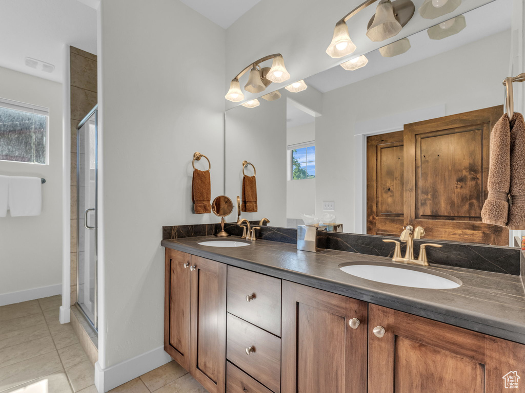Full bathroom with double vanity, a shower stall, tile patterned flooring, and baseboards