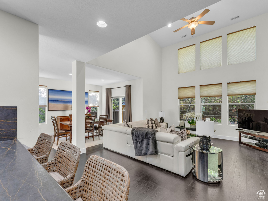 Living area with ceiling fan, dark wood finished floors, recessed lighting, a high ceiling, and baseboards