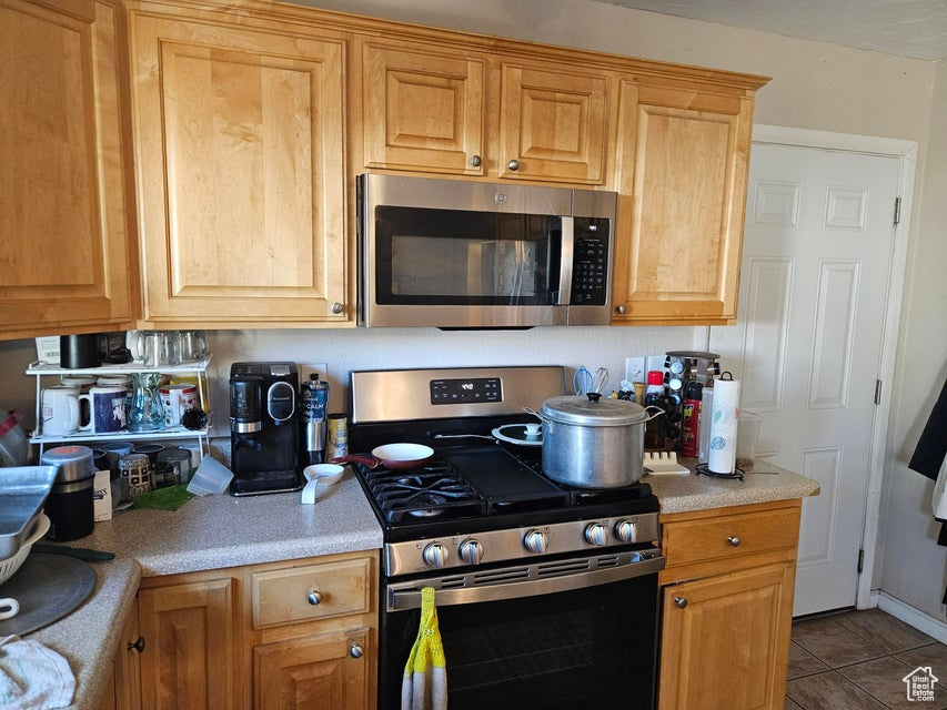 Kitchen with appliances with stainless steel finishes, light countertops, and tile patterned flooring