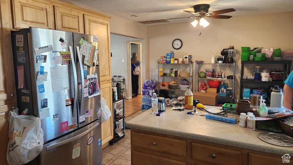 Kitchen featuring light tile patterned flooring, ceiling fan, water heater, light countertops, and light brown cabinetry