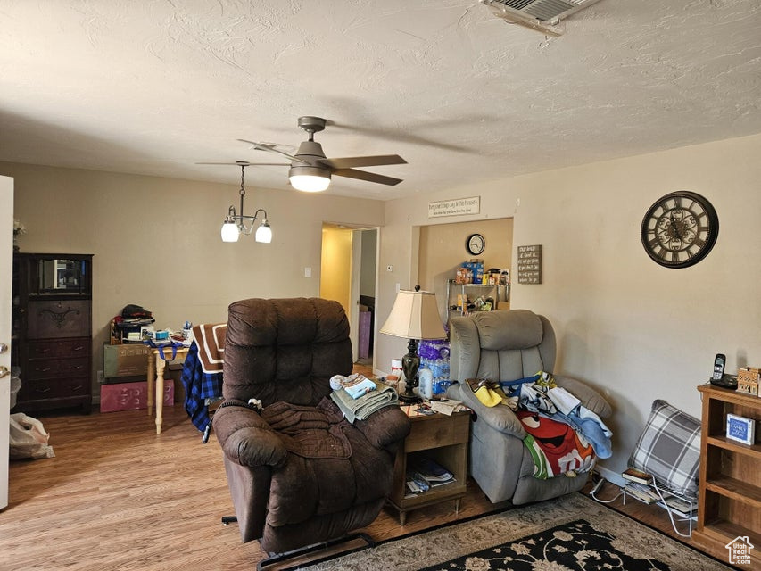 Living room featuring light wood-type flooring, a ceiling fan, and a textured ceiling