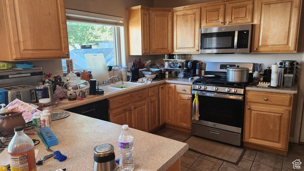 Kitchen with appliances with stainless steel finishes, light countertops, and tile patterned floors