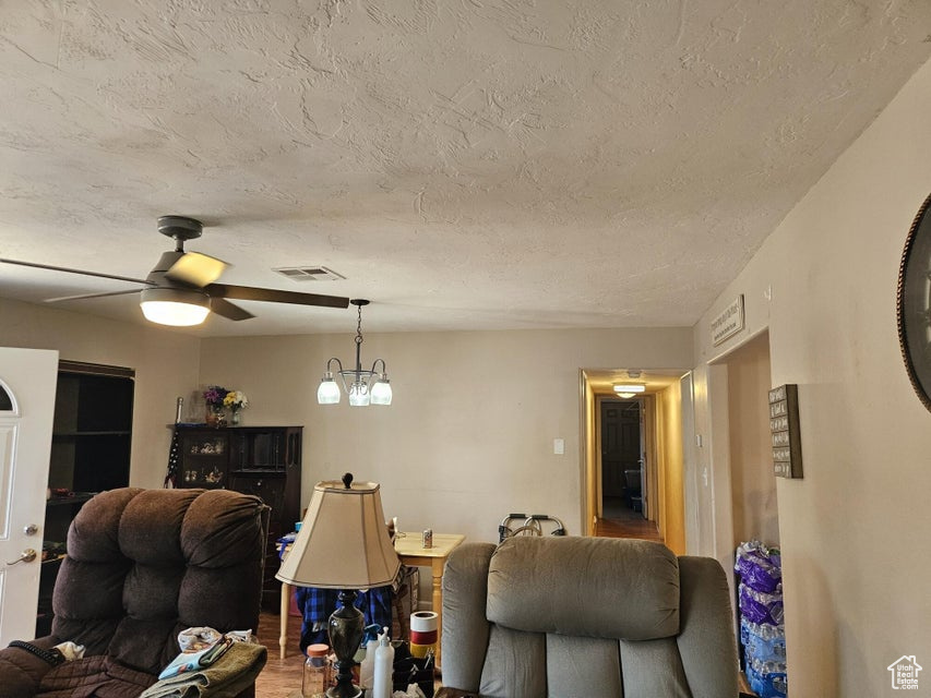 Living area featuring a ceiling fan, a textured ceiling, and a chandelier