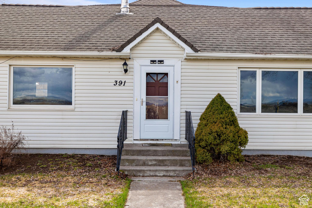 Entrance to property with roof with shingles