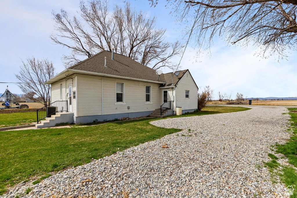 Back of house featuring a shingled roof and a yard