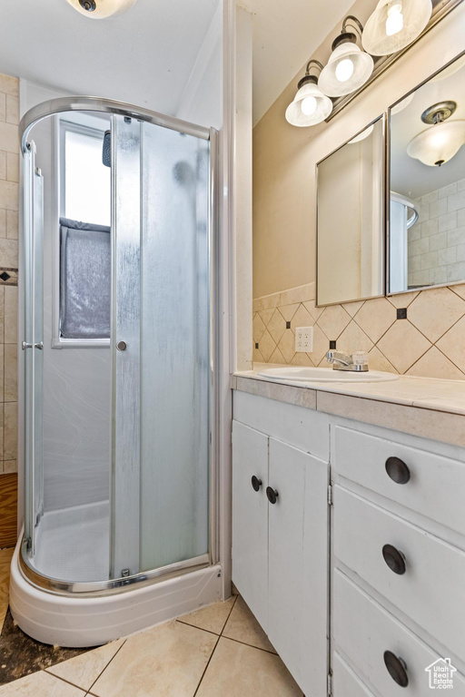 Bathroom featuring a shower stall, tile patterned floors, vanity, and backsplash