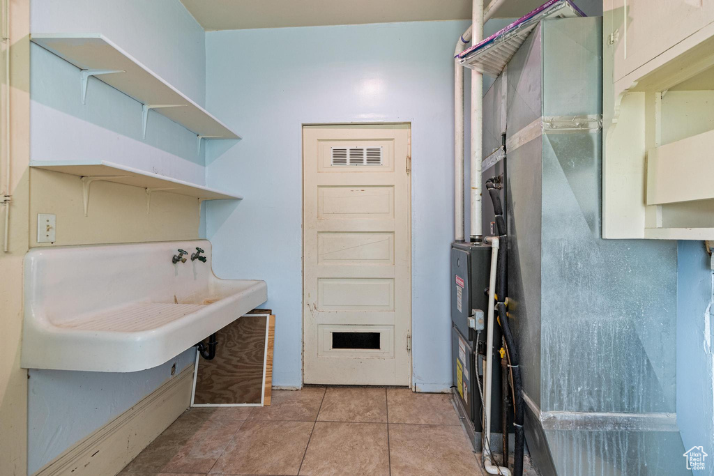 Laundry area featuring light tile patterned flooring, laundry area, and a sink