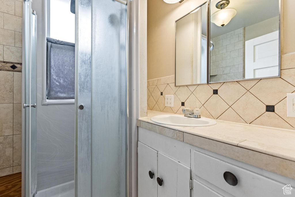 Bathroom featuring a shower, vanity, and decorative backsplash