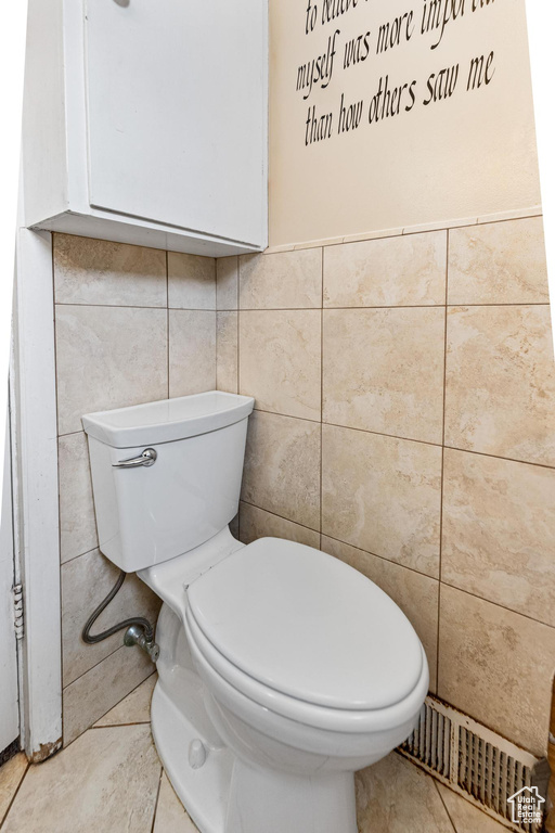 Bathroom featuring tile walls, visible vents, toilet, and tile patterned floors