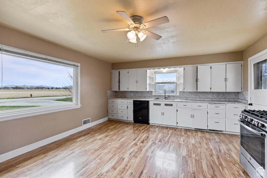 Kitchen with light countertops, stainless steel range with gas stovetop, decorative backsplash, a sink, and visible vents