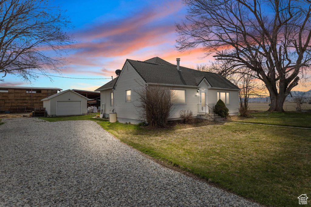 View of front of home featuring driveway, a front yard, an outdoor structure, entry steps, and a detached garage