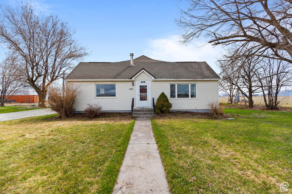 View of front of home with a shingled roof and a front lawn